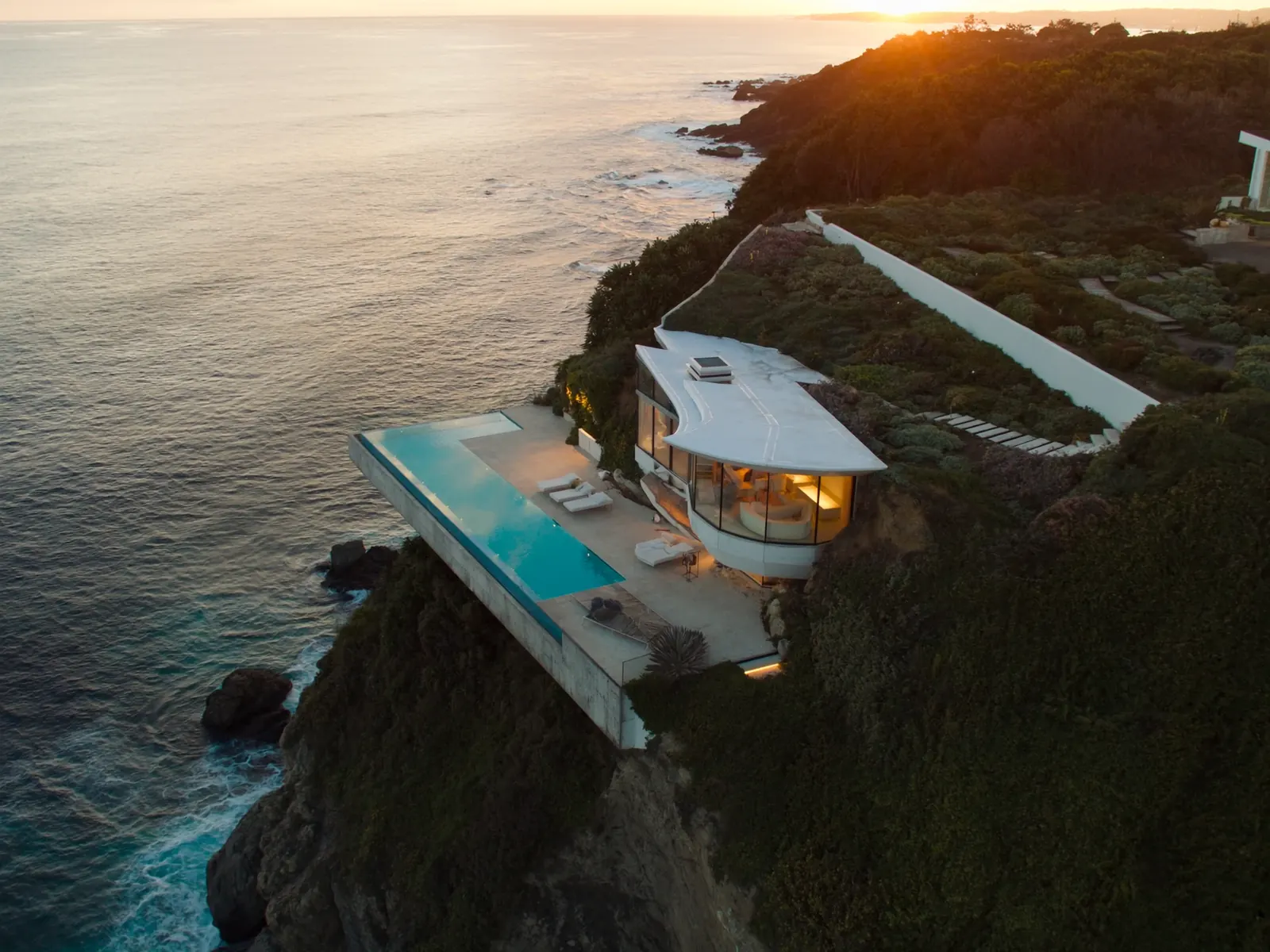 Meridian, an invented luxury real estate website concept: a cliffside villa with an infinity pool above the sea at sunset.